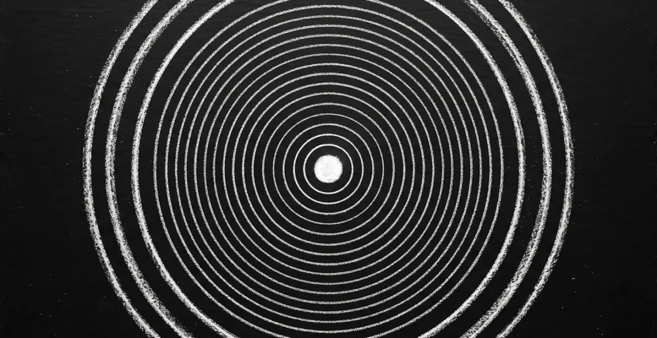 Cercles concentriques tracés à la craie blanche sur ardoise noire partant d'un centre lumineux vers l'extérieur, symbolisant transmission patrimoniale protégée